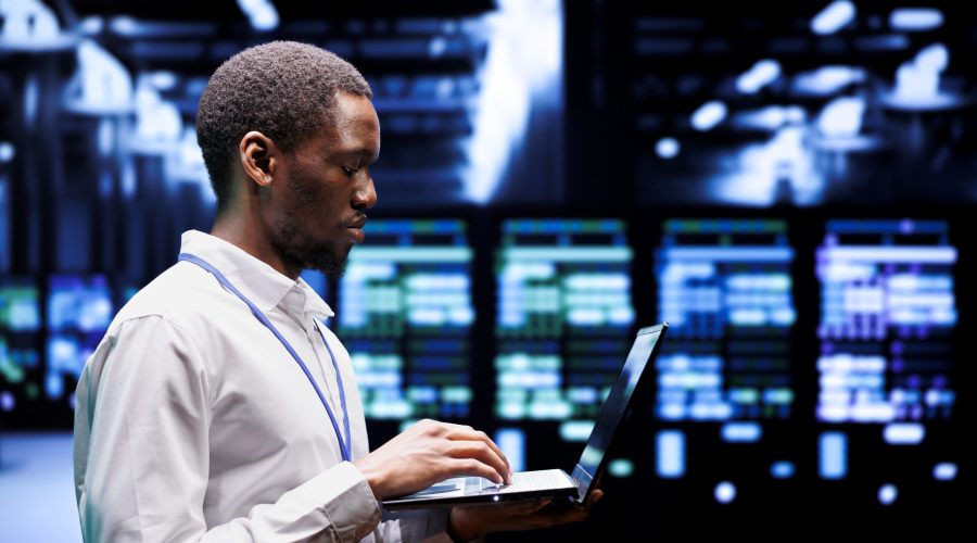 African american system administrator typing supercomputer hub contingency plan on laptop to provide fast restoration of service, limiting damage and minimizing interruptions to normal operations